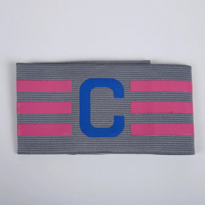 A grey football captain armband with pink stripes and a blue "C."